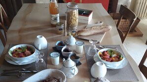 A dining table with various food items, including bread, pastries, and a cake, along with several cups and a bottle. - Bed and Breakfast 'Chambre Lavande' with Shared Terrace, Shared Garden and Wi-Fi (Eaux-Puiseaux)