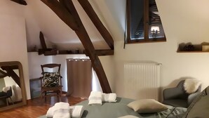 Un dormitorio con cama, dos sillas, un espejo, una ventana con persianas y un radiador.