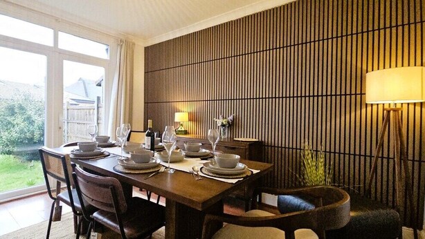A dining area with a table set for four, a lamp, and a view of the outdoors. - Spacious Home Near Wembley with Parking & Garden (Harrow)