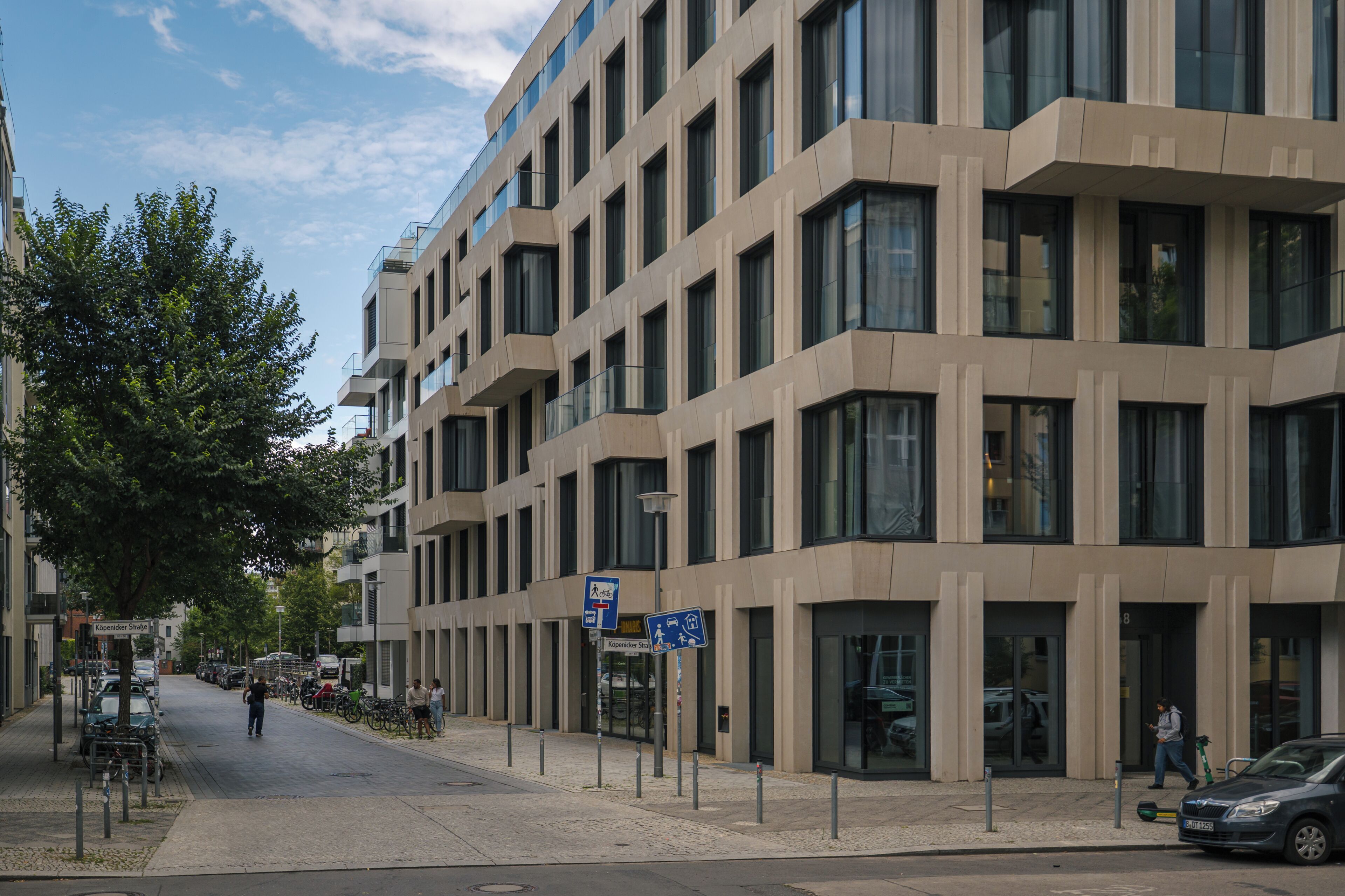 A modern building with multiple floors, large windows, and a pedestrian walkway.
