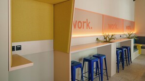 A modern workspace with a long counter, blue stools, and a wall with the word 'work.' - Homaris K48 Studios (Berlin)