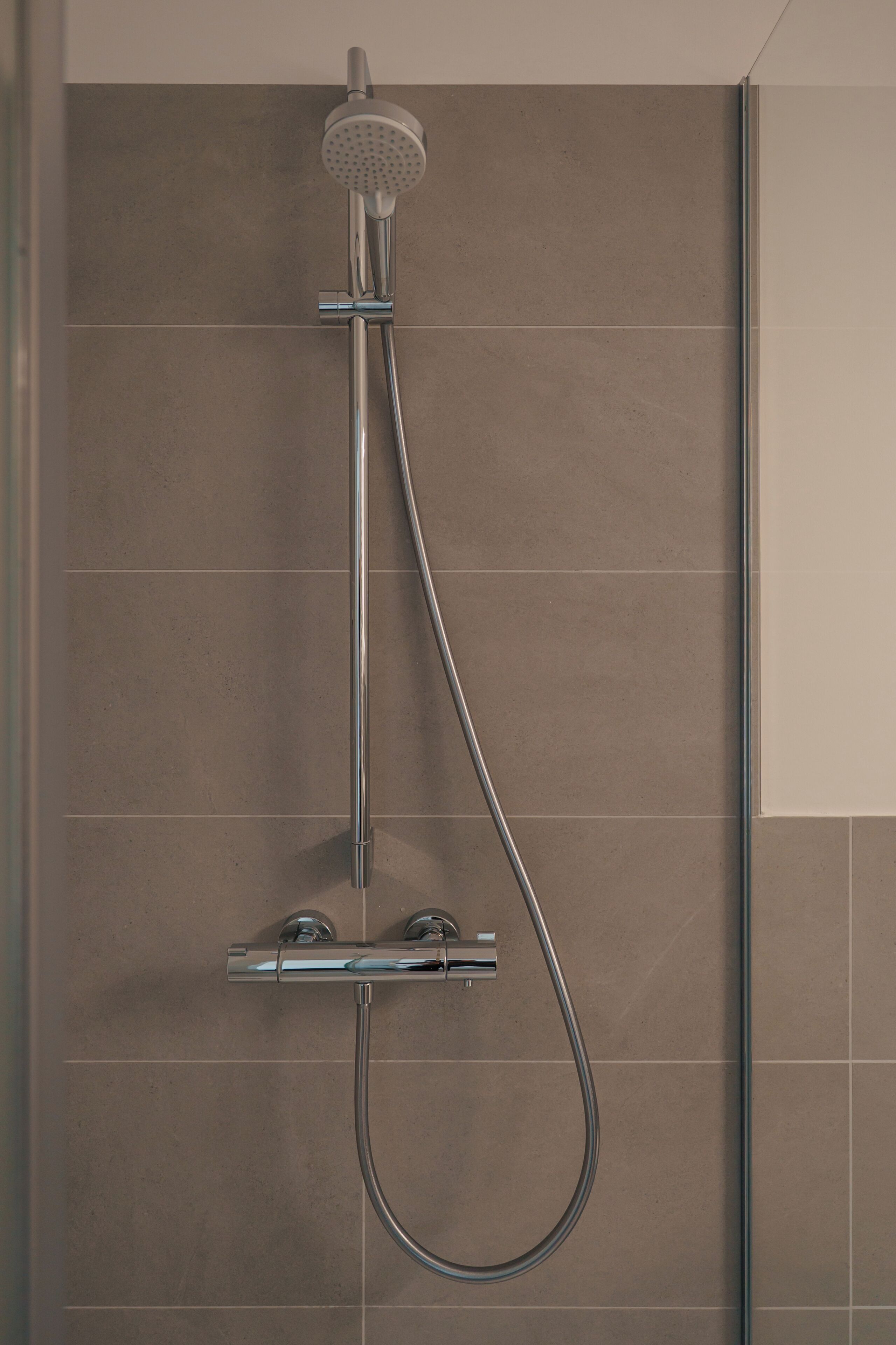 Een douche met een handdouche en een flexibele slang.