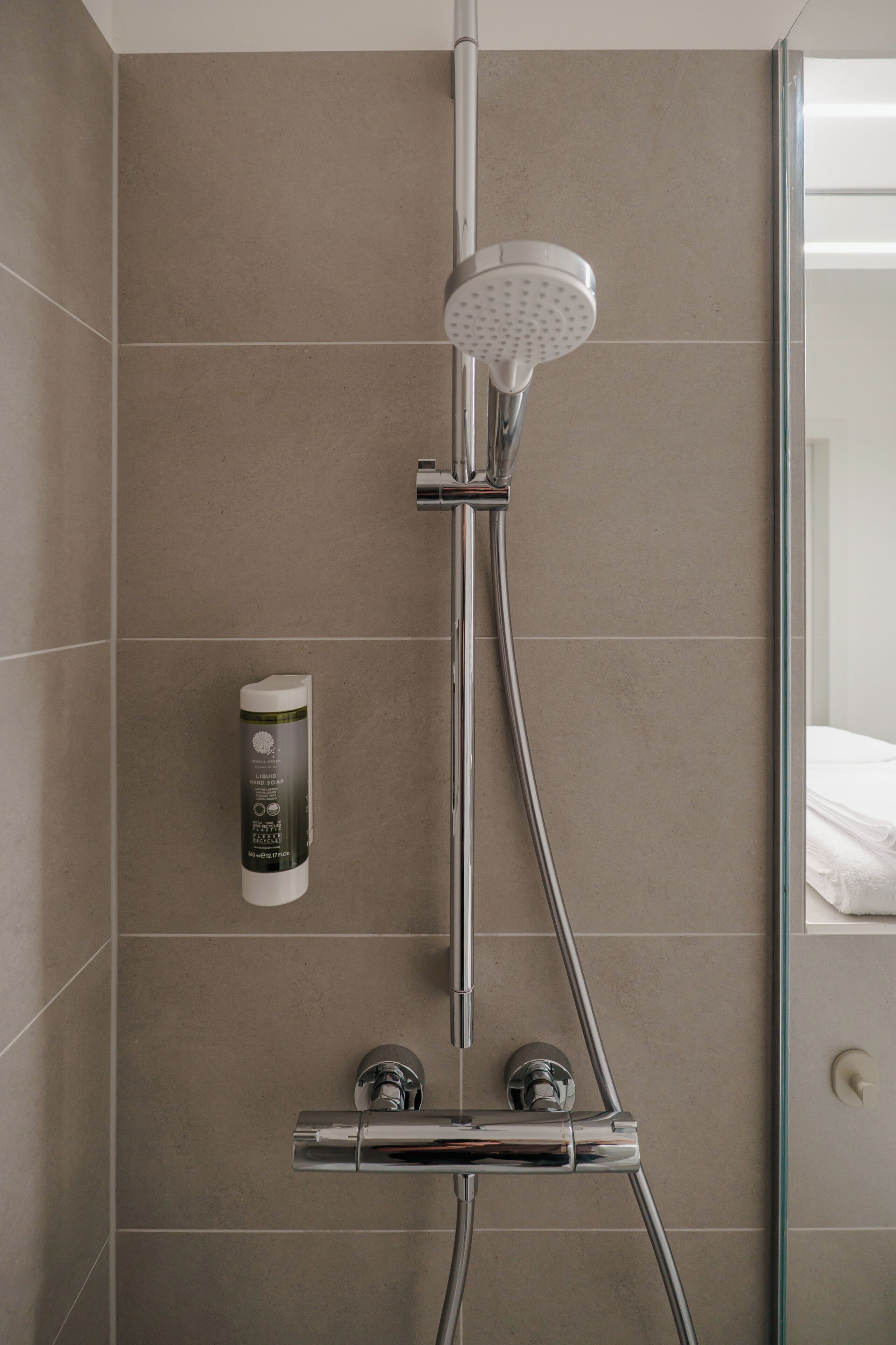 Une douche équipée d’un pommeau de douche à main, d’un distributeur de savon à main et d’un panneau de commande.