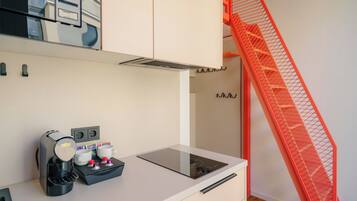 A kitchenette with a coffee maker, mugs, and a toaster.