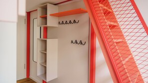 A modern interior with a white wardrobe, red accents, and a mesh partition. - Homaris K48 Studios (Berlin)