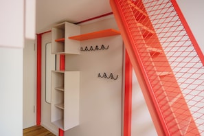 A modern interior with a white wardrobe, red accents, and a mesh partition. - Homaris K48 Studios (Berlin)