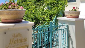 A villa named Villa Matakia with a white exterior, green shutters, and a blue metal gate.