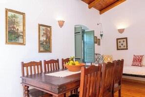Un'area pranzo con un tavolo e sedie in legno, una ciotola di frutta e due quadri appesi al muro.