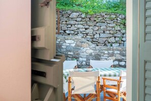 Un muro di pietra e un tavolo con sedie in un ambiente esterno.
