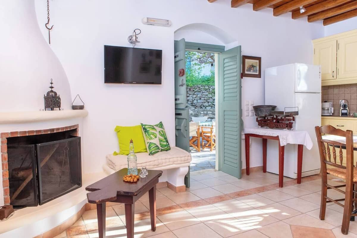 A cozy living room with a fireplace, a television, and a dining area with a table and chairs.