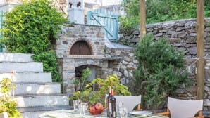 An outdoor dining area with a stone oven, a checkered tablecloth, and a rustic setting.
