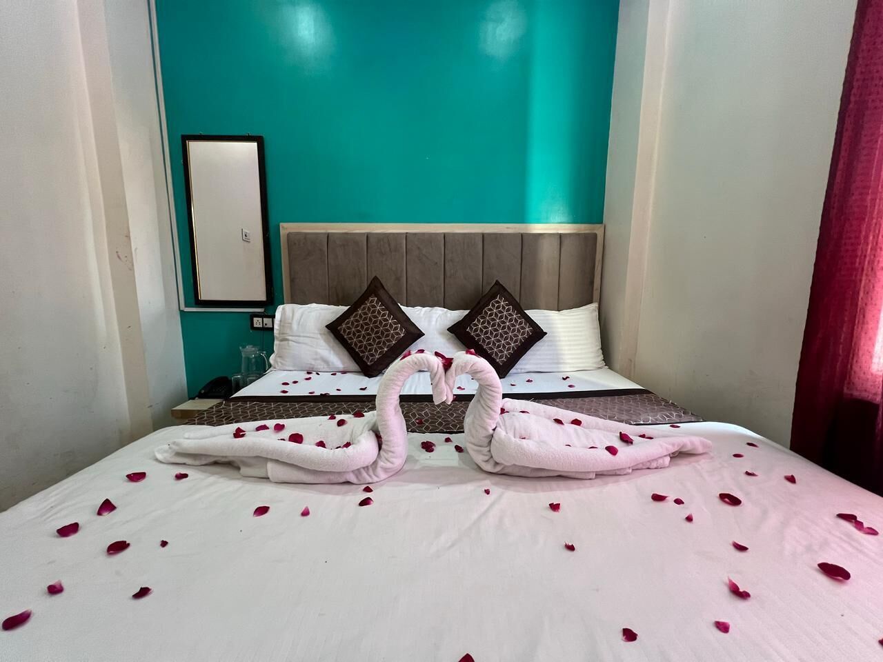 A hotel room with a bed, a headboard, and a mirror on the wall.