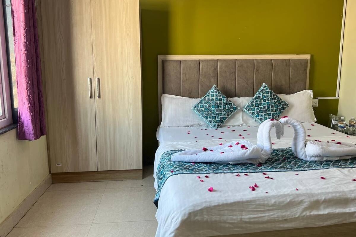A bedroom with a bed, two pillows, a wardrobe, and a window with curtains.