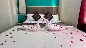 A hotel room with a bed adorned with rose petals and two towels shaped like swans. - Shri Hari Kripa Residency (Varanasi)
