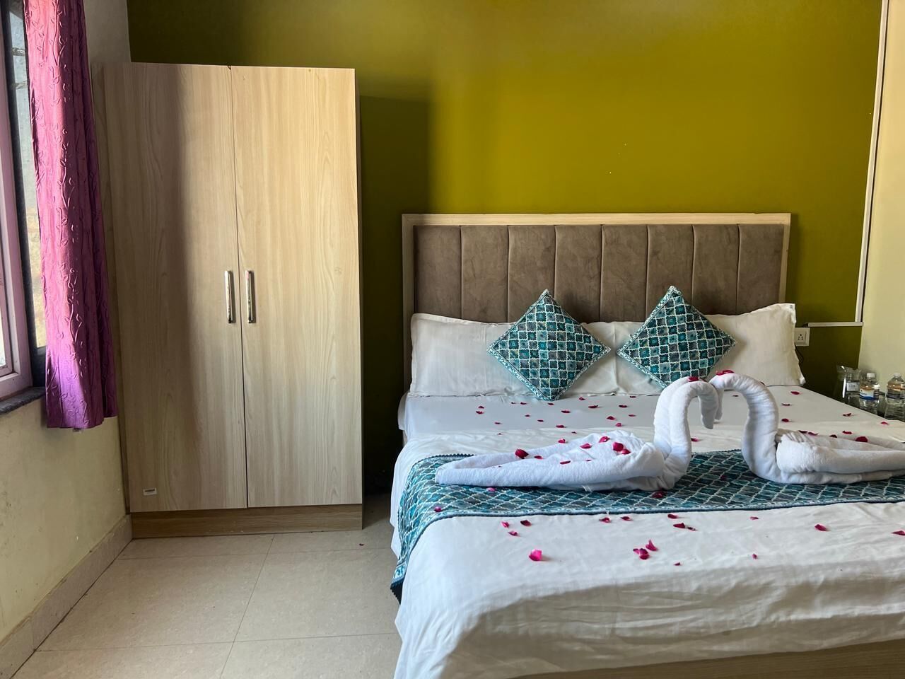 A hotel room with a bed, a wardrobe, and a window with curtains.
