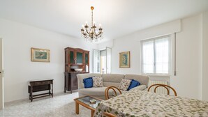 Ein Zimmer mit einem Bett, einem Schlafsofa, einem Holztischchen, einer kleinen Kommode und einer Deckenleuchte.