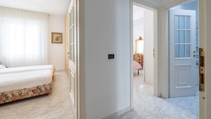 Ein Hotelzimmer mit einem Bett, einer Tür zu einem anderen Raum und einem Flur mit einer Tür.