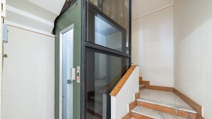 Eine Treppe mit Marmorstufen und einer Glastür für einen Aufzug.