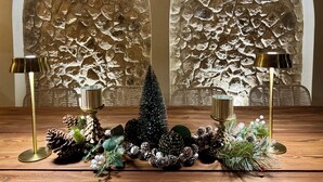 A wooden table with a decorative arrangement including pine cones, greenery, and a small Christmas tree. Two lamps with gold bases are placed on either side of the table. - La villa DUCASSE (Ounagha)