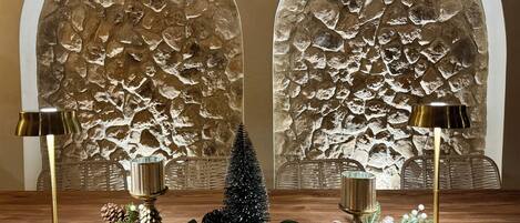 A wooden table with a decorative arrangement including pine cones, greenery, and a small Christmas tree. Two lamps with gold bases are placed on either side of the table.