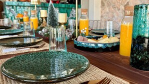 A dining table set with green plates, cutlery, and a woven placemat. - La villa DUCASSE (Ounagha)