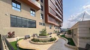 Un edificio moderno con un cortile che include posti a sedere all'aperto, una fontana e erba sintetica.