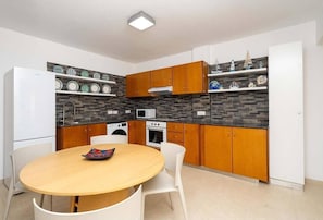 A compact kitchen with a central island, wooden cabinets, and a microwave.