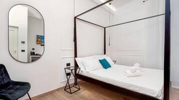 Een moderne slaapkamer met een hemelbed, een ronde spiegel en een zwarte stoel.