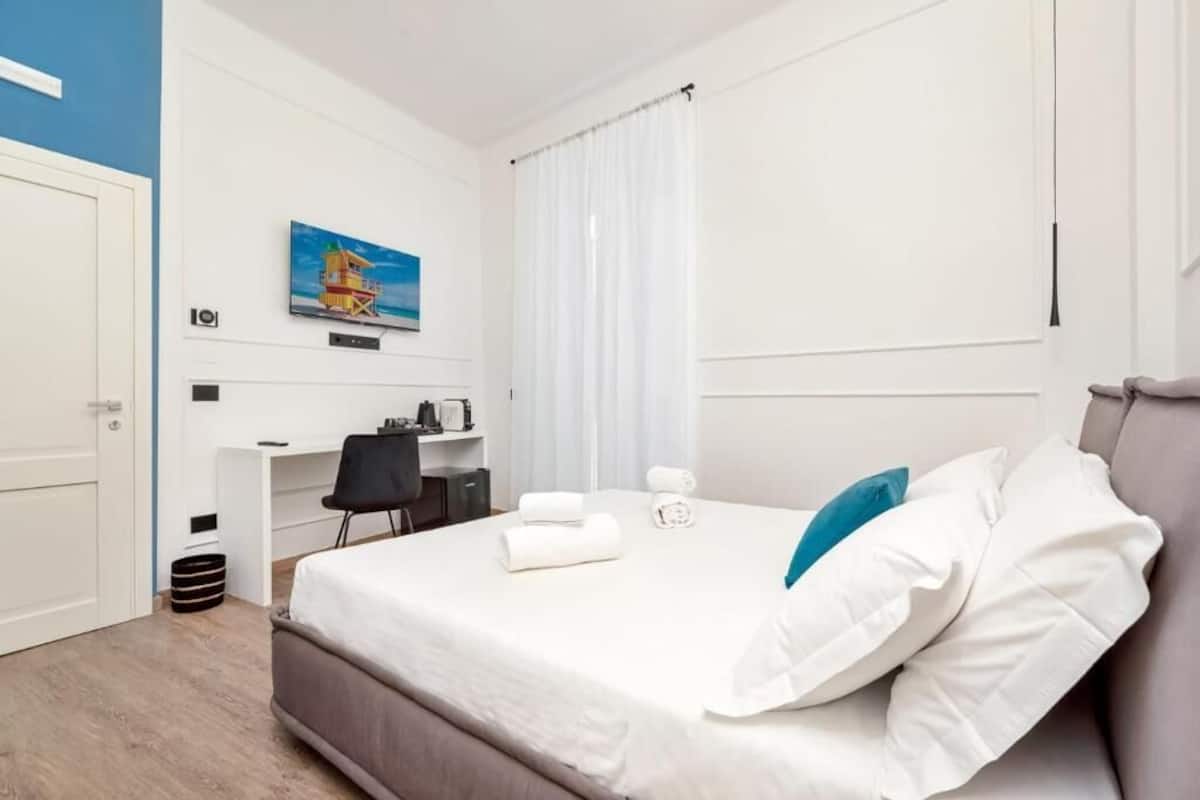 Een hotelkamer met een bed, een bureau, een stoel en een schilderij aan de muur.