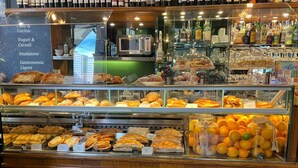 Une vitrine de boulangerie présentant diverses pâtisseries et une sélection de boissons en bouteille.