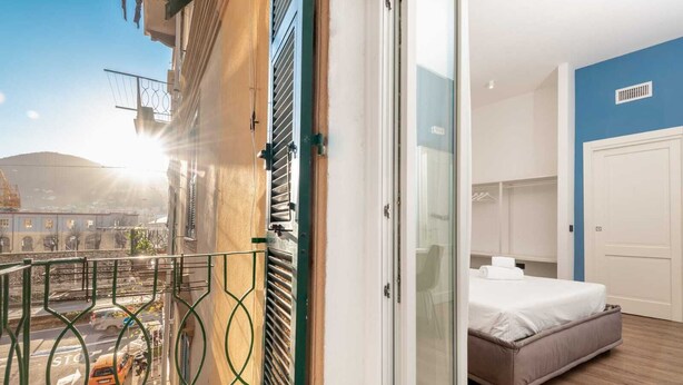 Une chambre d’hôtel avec un lit, une salle de bain et un balcon donnant sur la ville.