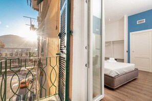 Une chambre d’hôtel avec un lit, une salle de bain et un balcon donnant sur la ville.