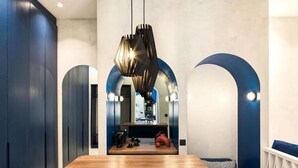 Una cocina moderna con encimera de madera, una lámpara colgante y un rincón de estar con un sofá azul y cojines.