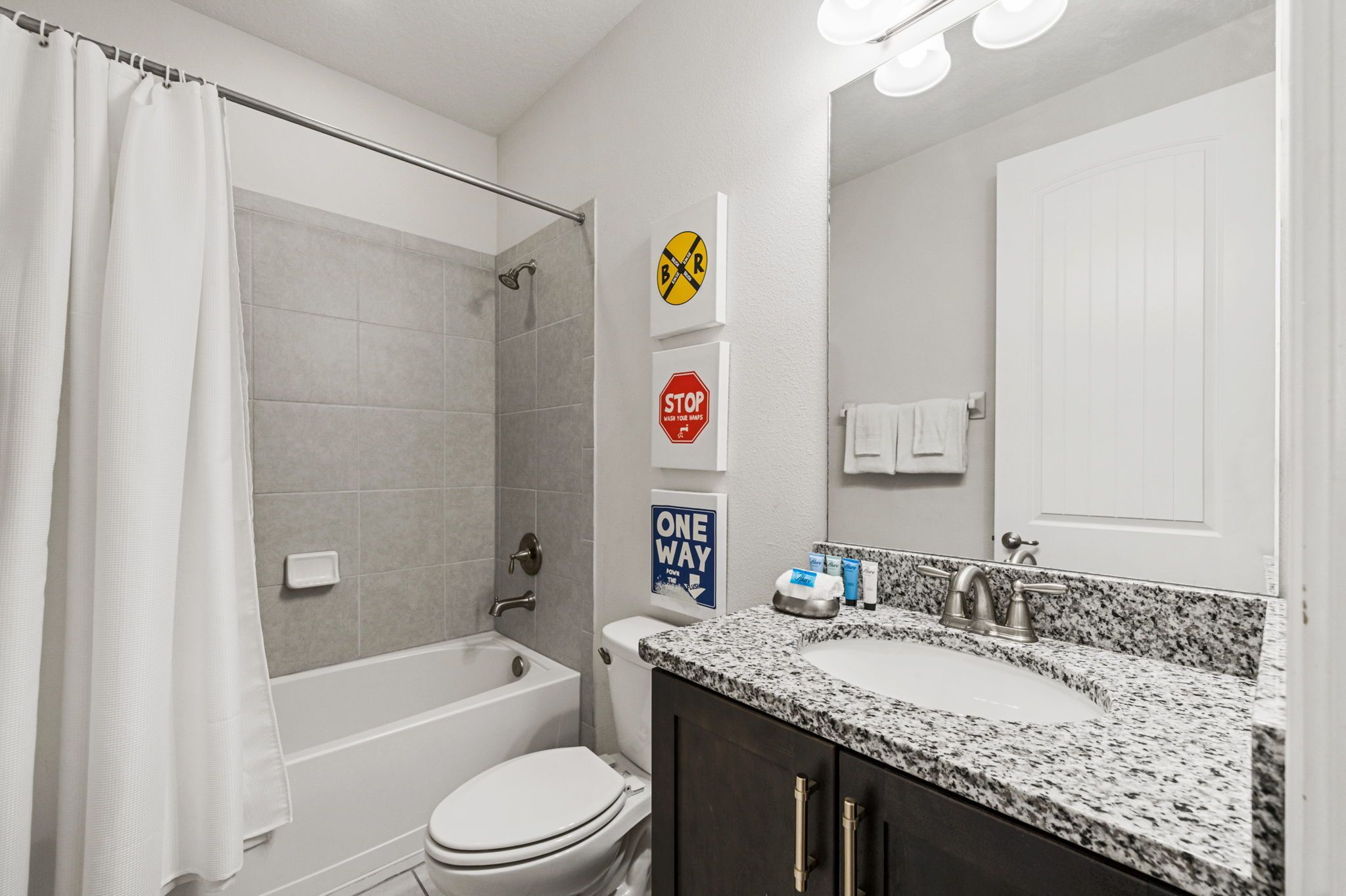 Een moderne badkamer met douche, toilet en wastafel.