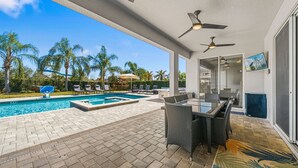 A covered outdoor area with a pool, lounge chairs, and a dining table. - 251 Falls Drive (Kissimmee)