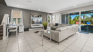 A modern living room with a sofa, TV, and dining area. - 251 Falls Drive (Kissimmee)