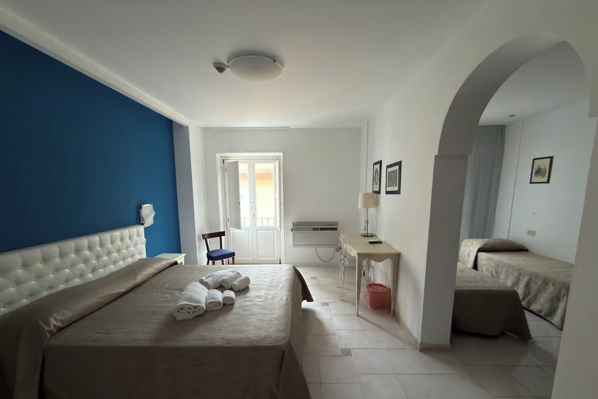 Una habitación de hotel con una cama grande, un escritorio con lámpara, una silla y una mesita.