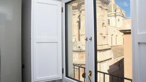 Ein Zimmer mit einer weißen Tür und Blick auf historische Gebäude durch eine Glastür.