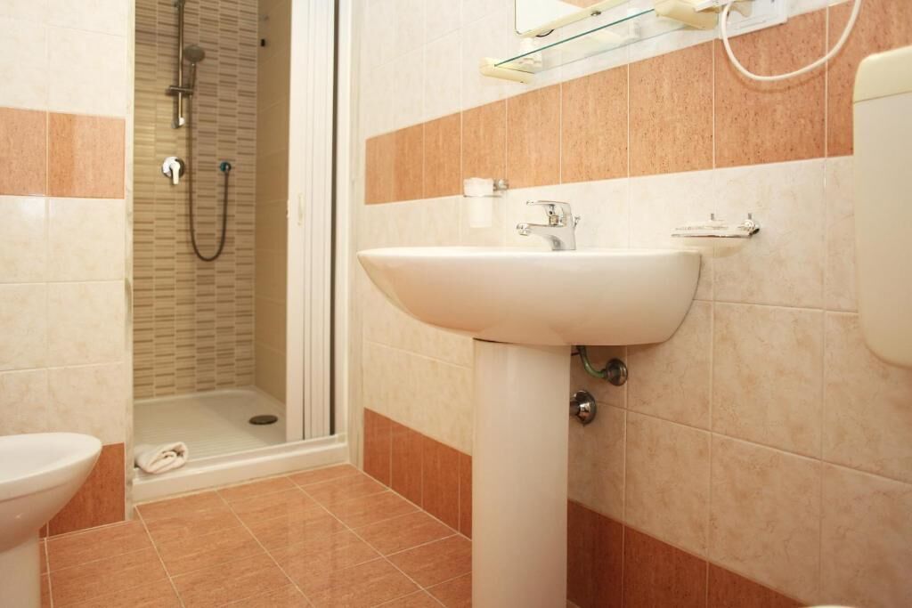 Une salle de bain avec douche, toilettes et lavabo.