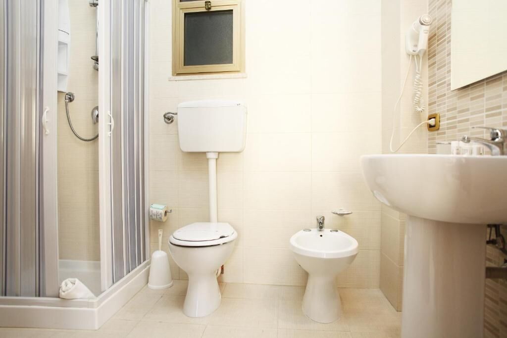 A bathroom with a shower, toilet, bidet, and sink.