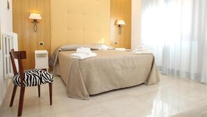 Ein Hotelzimmer mit einem großen Bett, zwei Nachttischlampen, einem Stuhl mit ZEBRA-Muster und einem Heizkörper.