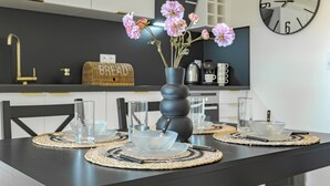 Una cucina moderna con un piano di lavoro nero, un vaso con fiori rosa e una sveglia a parete.