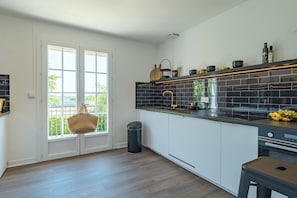 Une cuisine moderne avec des meubles blancs, un pare-feu noir et une fenêtre offrant une belle vue.