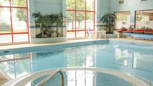 An indoor swimming pool with clear blue water, surrounded by large windows and potted plants. - Holiday Cabin Sleeps 5, Pets, Edinburgh Festival (Dunbar)