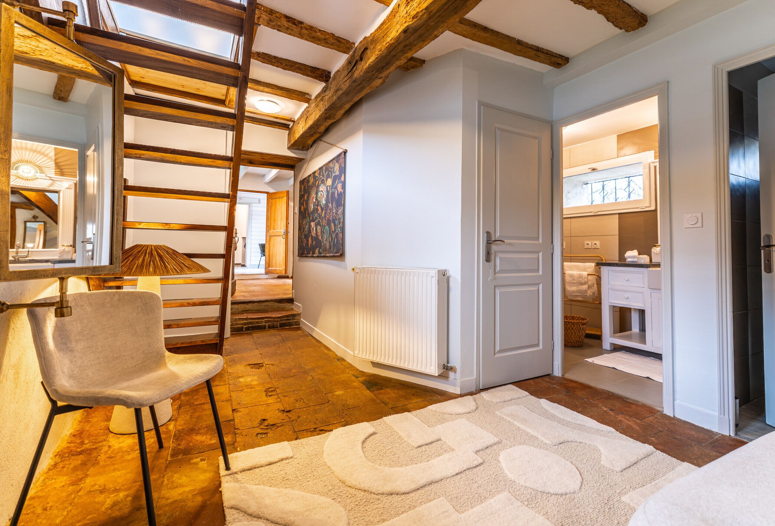 A modern interior with exposed wooden beams, a white radiator, a large mirror, and a chair.