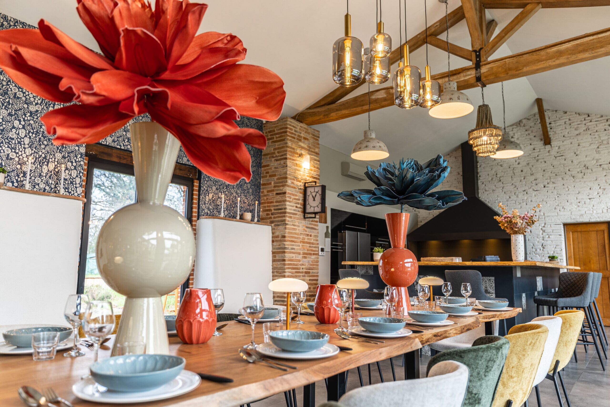 Un comedor con una larga mesa de madera dispuesta para una comida, rodeada de sillas.