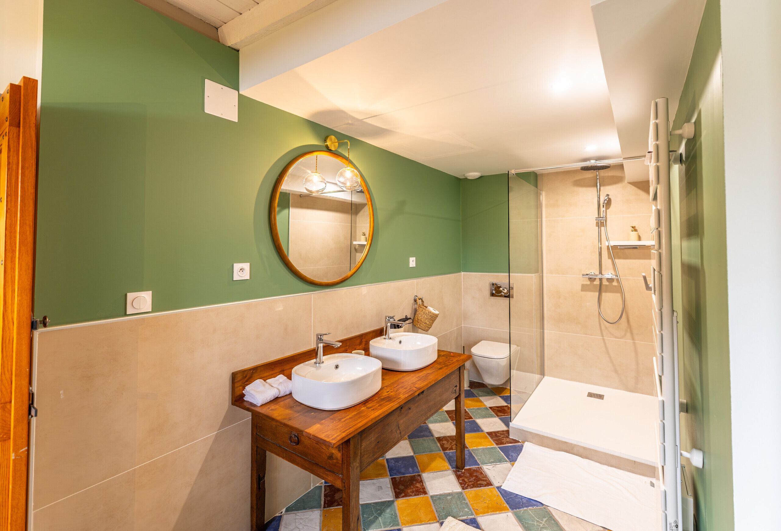 A bathroom with two sinks, a toilet, and a shower.