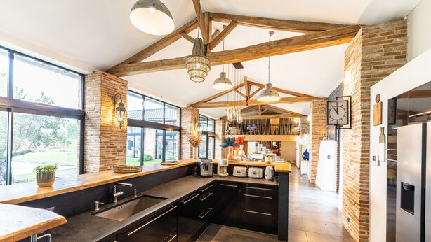 Una cocina moderna con paredes de ladrillo a la vista, ventanas amplias y una isla central.