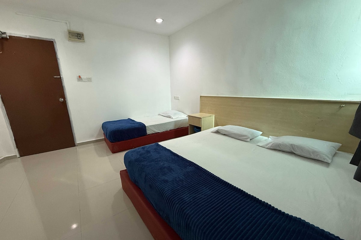 A hotel room with a large bed, a smaller bed, a wooden headboard, a nightstand, and a door.