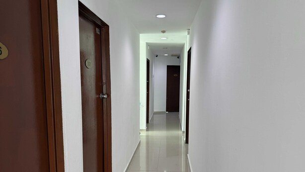 A clean, well-lit hallway with a wooden door on the left and a white wall. - OYO 91288 HOTEL PARADISE BATU CAVES (Selayang)
